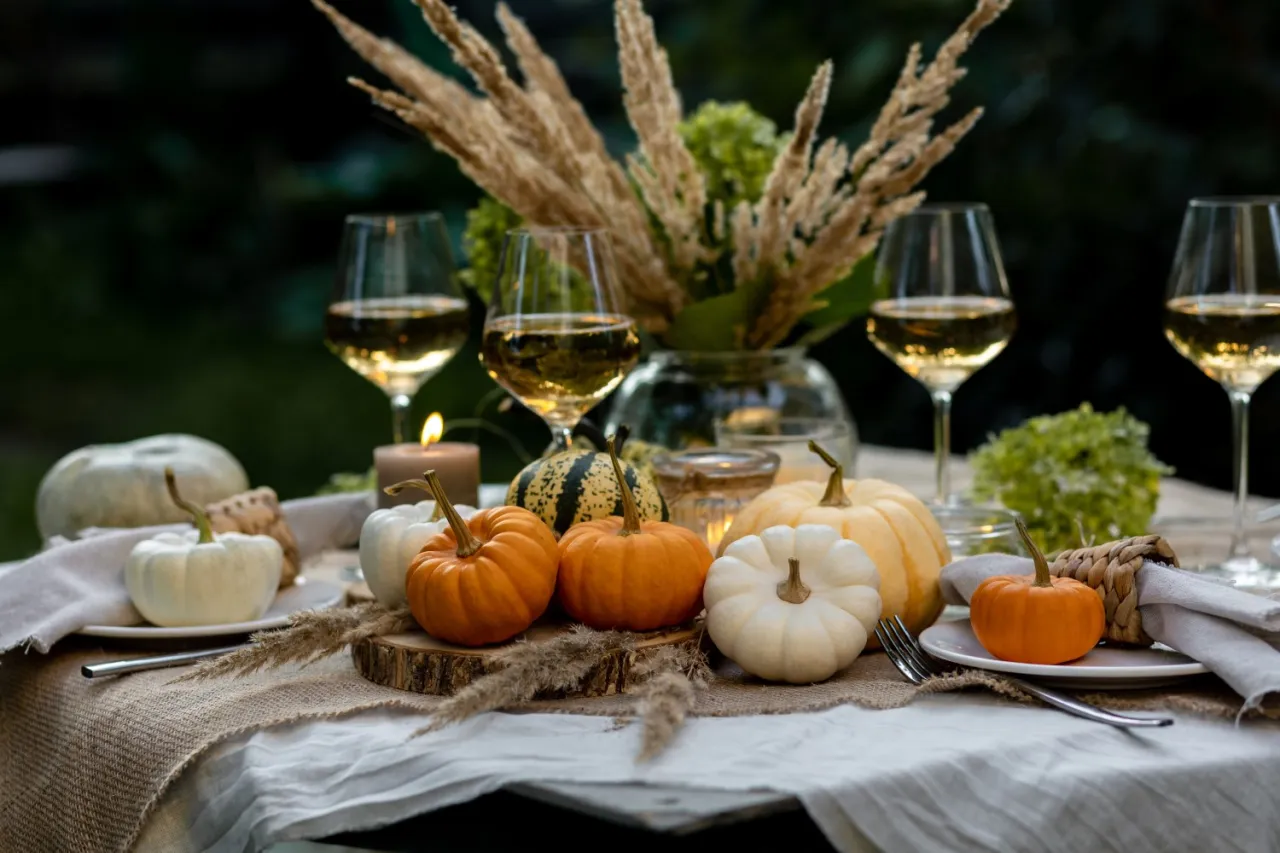 Jesienne dekoracje stołu z dyniami, świecami i winem. Wiele możliwości, co można zrobić z dyni, od ozdoby po pyszne potrawy.