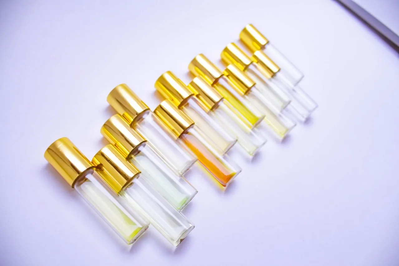 Rząd małych, szklanych flakoników z złotymi nakrętkami, wypełnionych płynami o różnych odcieniach. To próbki wód toaletowych z atomizerem, gotowe do odkrycia.