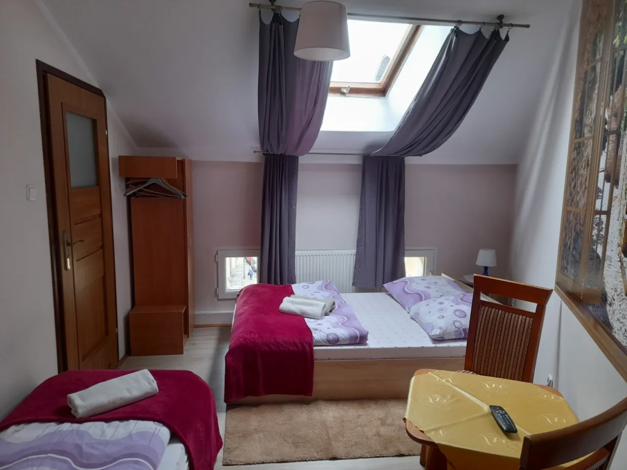 Pokój z dwoma łóżkami, szafą i stolikiem. Idealne miejsce, by sprawdzić, ile kosztuje nocleg w Krakowie.