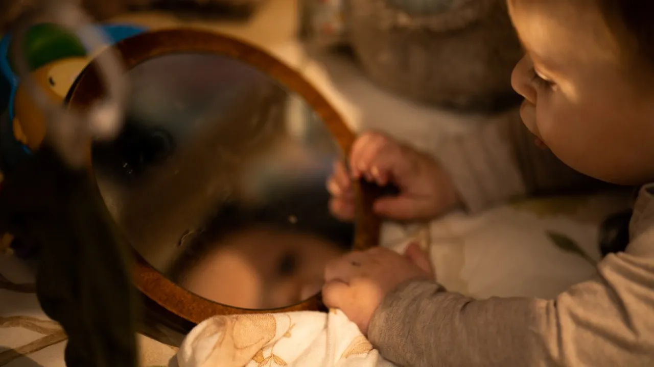 Małe dziecko z zaciekawieniem patrzy w lustro, odkrywając swoje odbicie. Czy niemowlę może patrzeć w lustro? Tak, to fascynujący moment rozwoju.