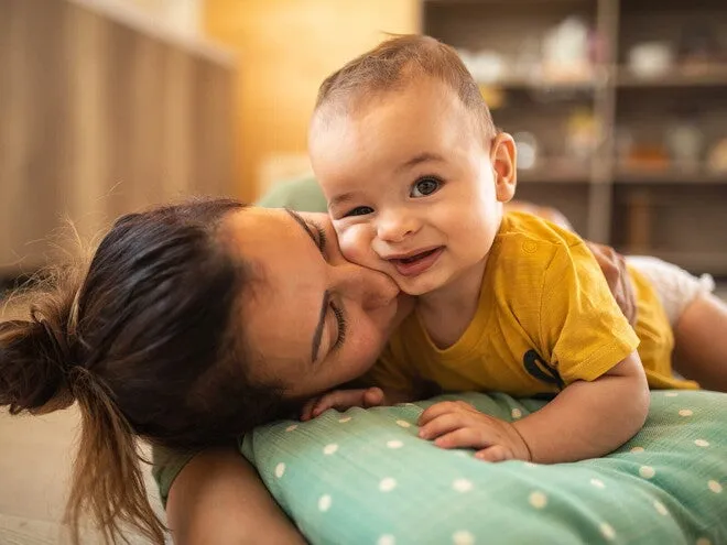szczęśliwe niemowlę w 4 miesiącu życia w objęciach rodzica