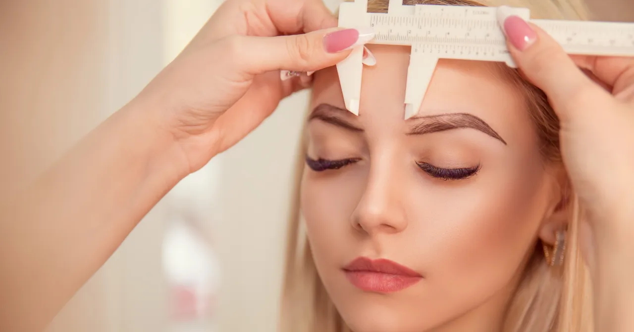 Precyzyjne mierzenie twarzy przed wykonaniem brwi permanentnych metodą włoskową.