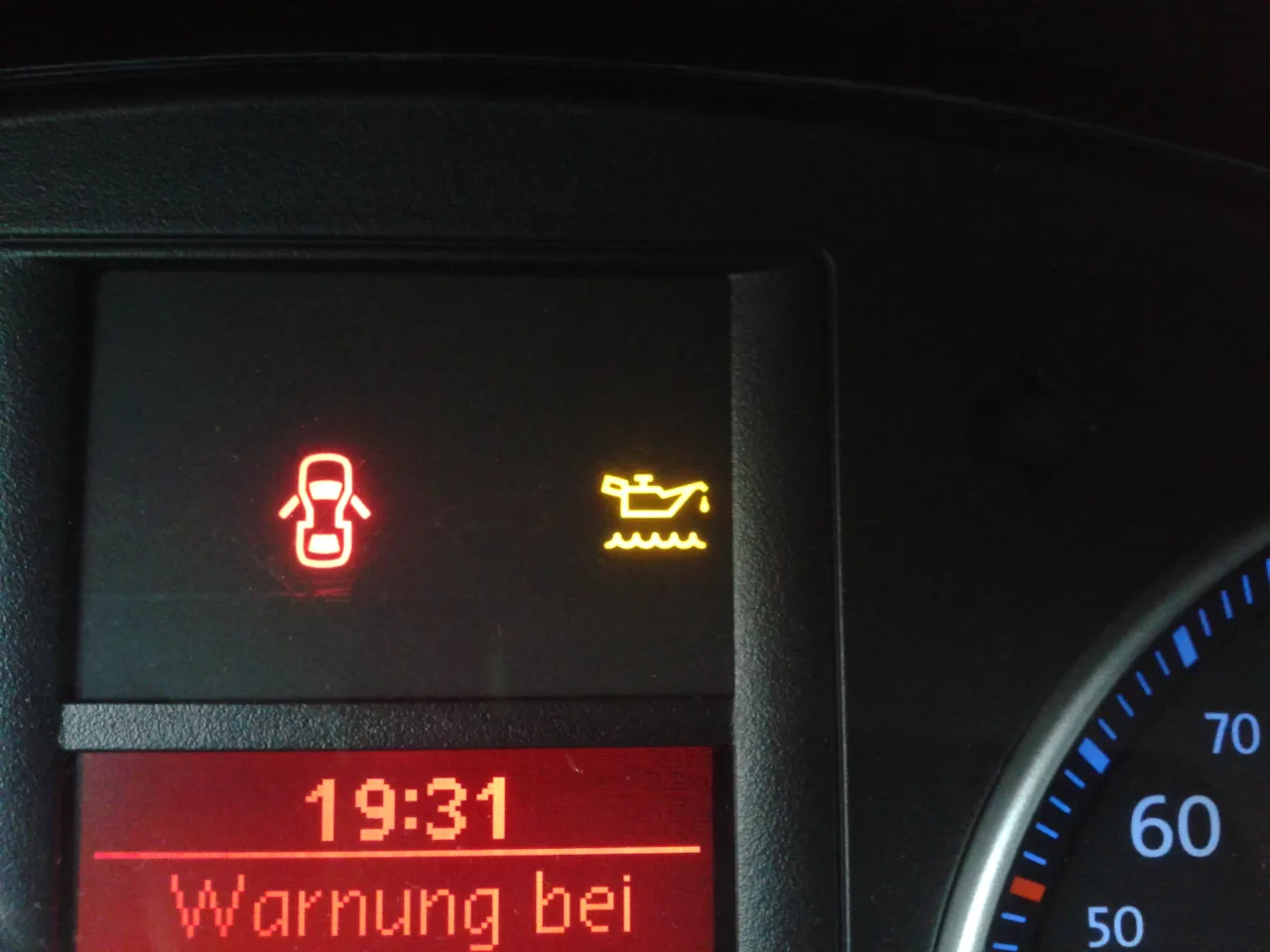 Kontrolka oleju świeci się na żółto, a obok niej świeci się kontrolka otwartych drzwi. Czas 19:31. Zastanawiasz się, ile można przejechać po zapaleniu się kontrolki poziomu oleju? Lepiej nie ryzykować.