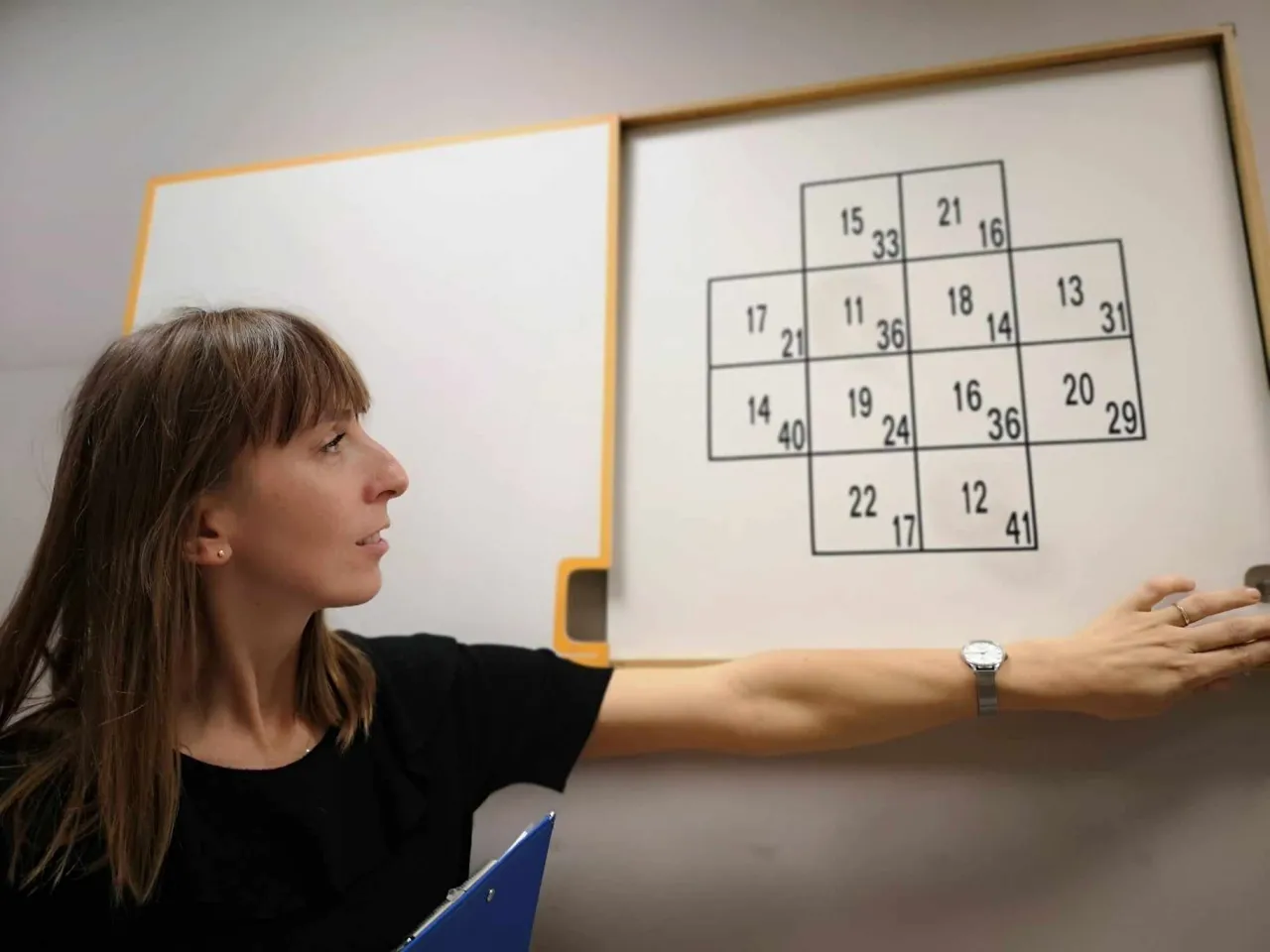 Psycholog wyjaśnia zadanie z tablicy, pokazując, ile trwają psychotesty dla kierowc&oacute;w.