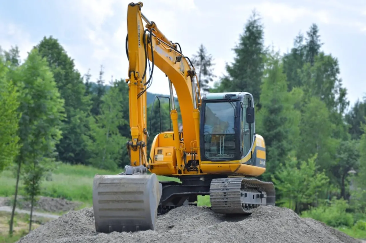 Ż&oacute;łta koparko-ładowarka na gąsienicach, gotowa do pracy. Uprawnienia na koparko ładowarkę do czego uprawniają? Do obsługi tej maszyny i wielu innych prac budowlanych.