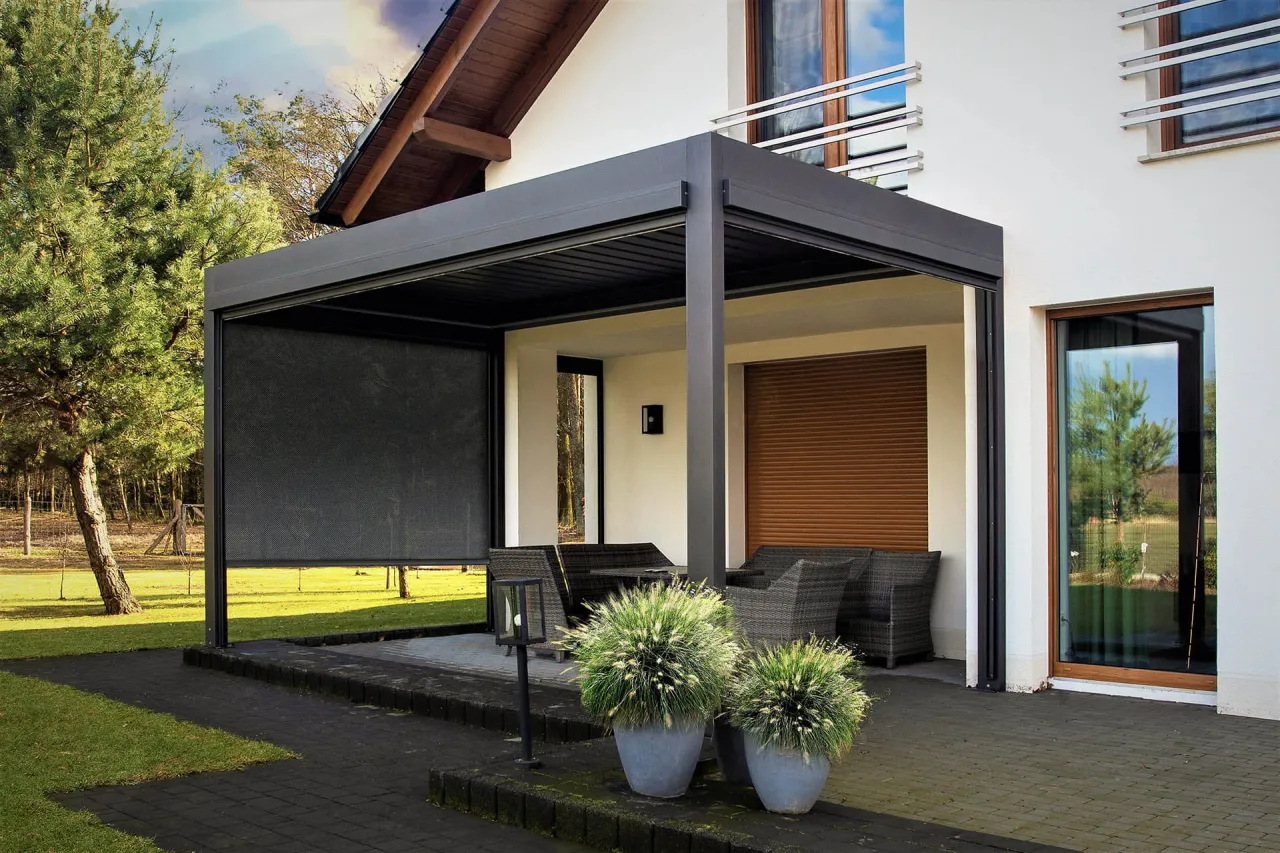 Nowoczesna pergola z zasłoną i meblami ogrodowymi. Zastanawiasz się, ile kosztuje zrobienie pergoli?