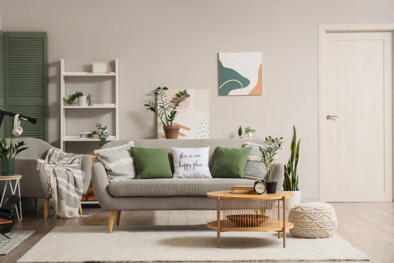 W salonie z dominującymi odcieniami zieleni, szara kanapa z zielonymi poduszkami i stolik kawowy tworzą przytulną przestrzeń.