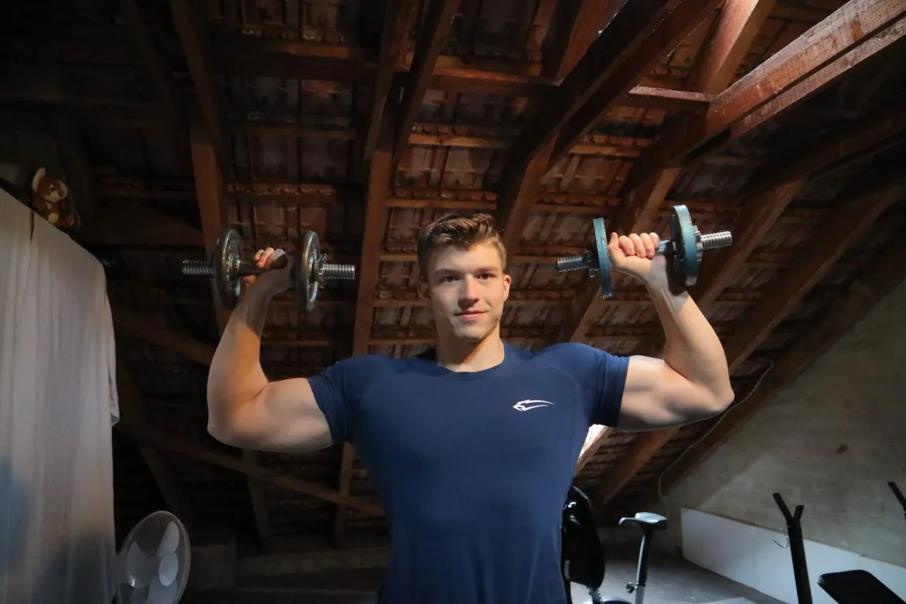 Mann trainiert Schulterdrücken mit Kurzhanteln im Sitzen