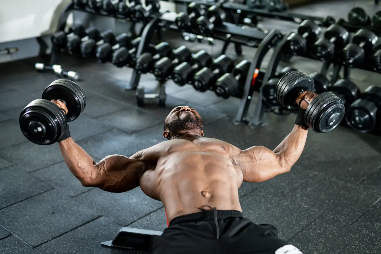Mann trainiert Brust mit Kurzhanteln auf Hantelbank