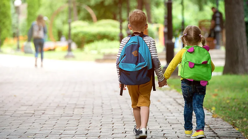 Rodzic trzymający dziecko za rękę idące do szkoły