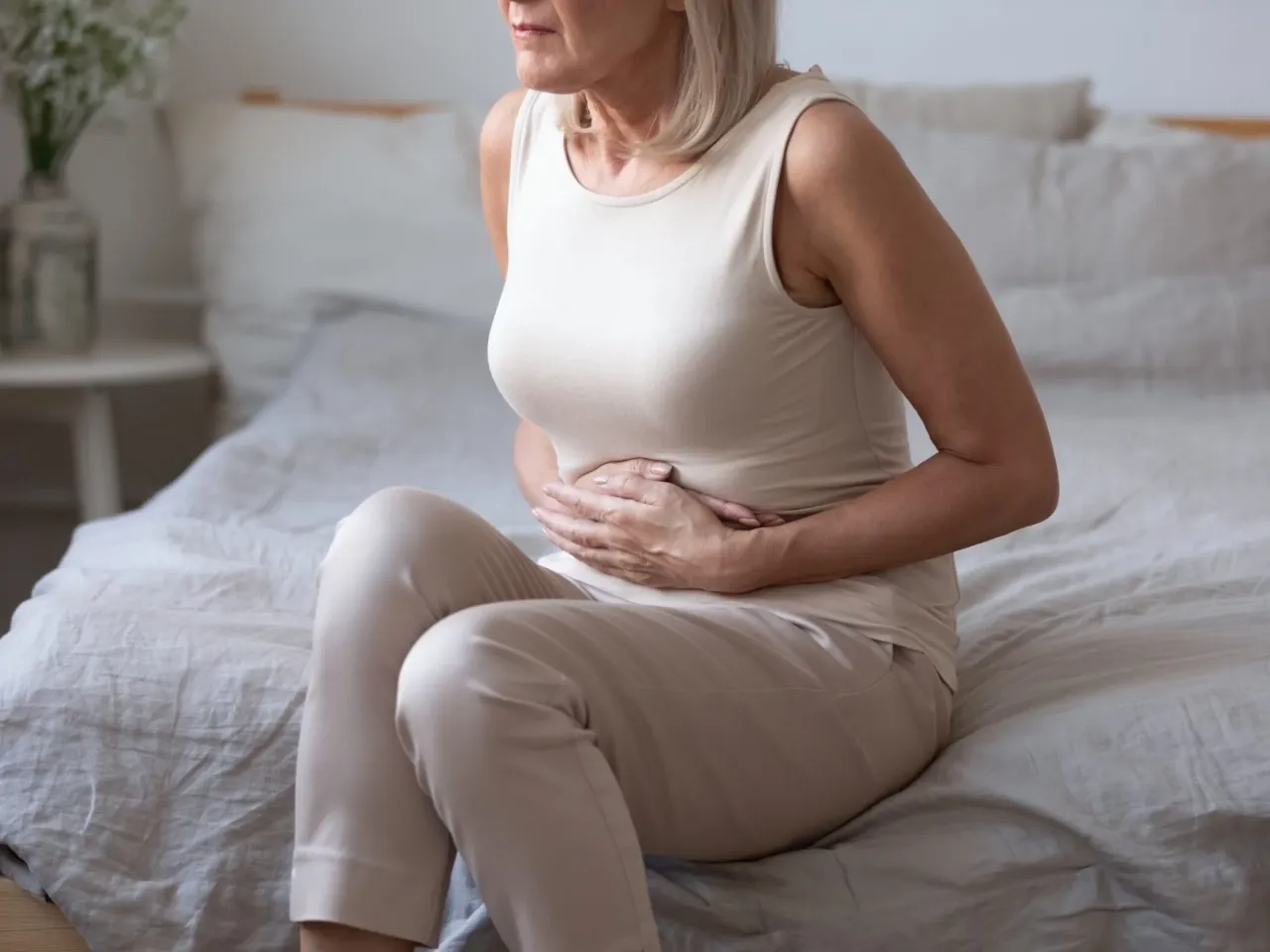 Osoba zamyślona, zaniepokojona, trzymająca się za brzuch