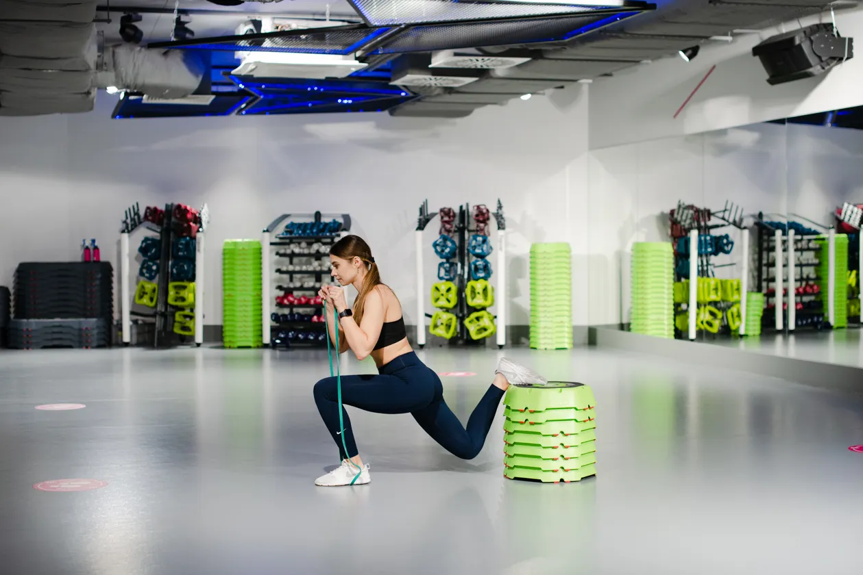 kobieta ćwicząca z gumą oporową na nogach, przysiad bułgarski