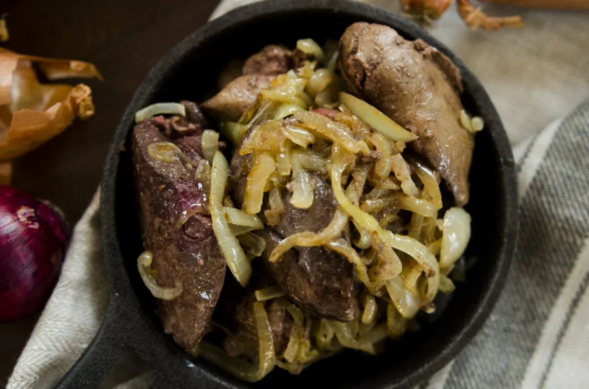 Wątr&oacute;bka drobiowa duszona z cebulką, idealna do domowych przepis&oacute;w na watrobke drobiowa. Obok cebula czerwona i łuska.