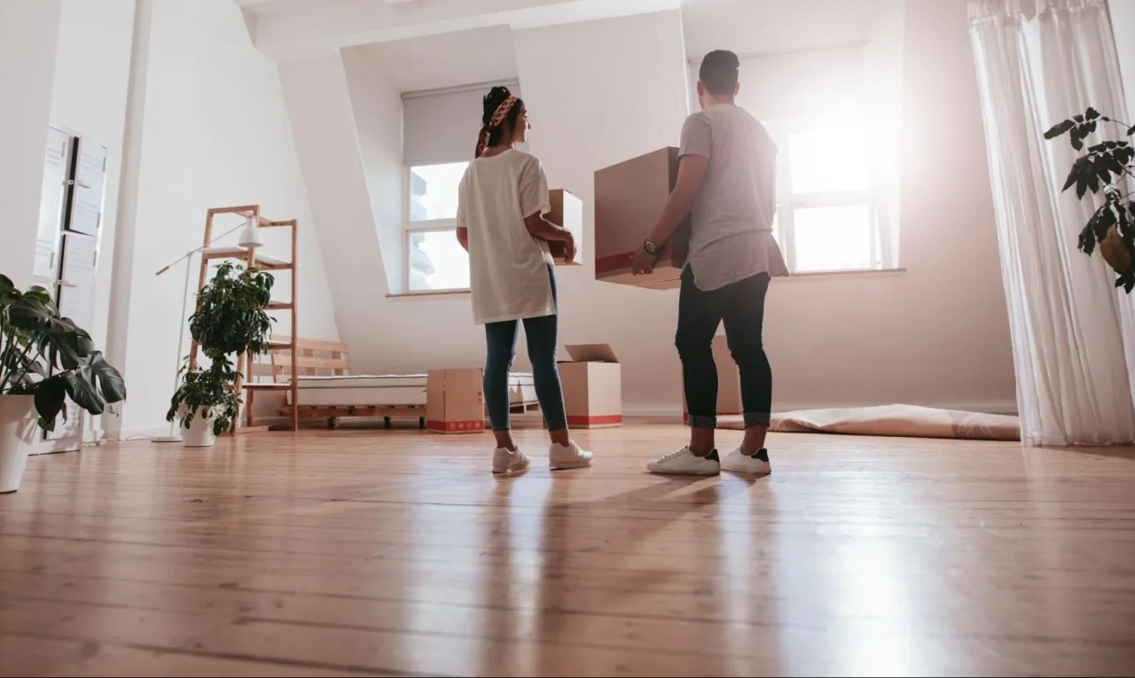Para młodych wnosi pudła do nowego mieszkania. To ich pierwszy wspólny dom, a odstępne za mieszkanie jest już opłacone.