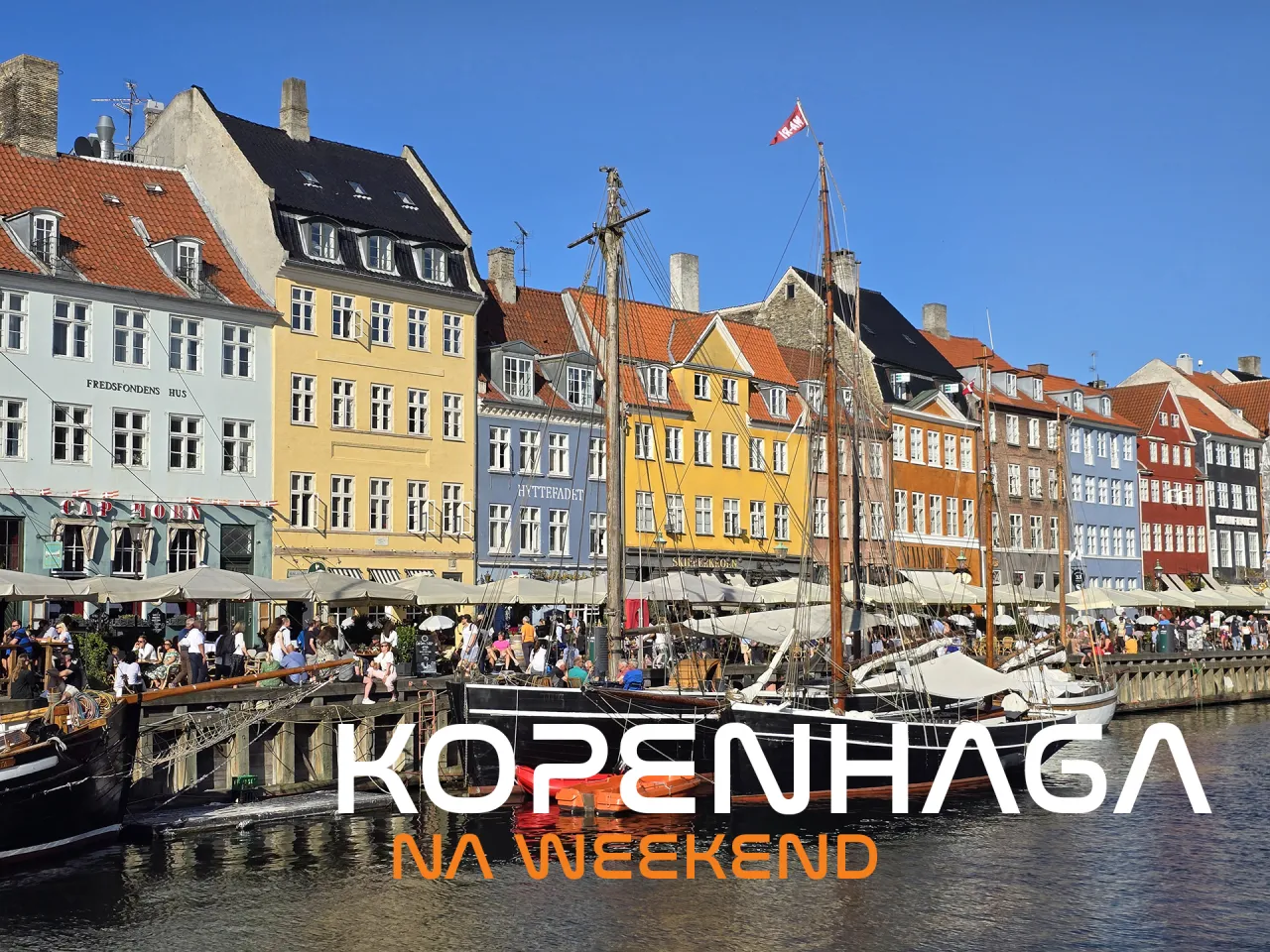 Kolorowe kamienice nad kanałem, żaglowce i ludzie &ndash; idealne miejsce, by zobaczyć, co zwiedzić w Kopenhadze na weekend.