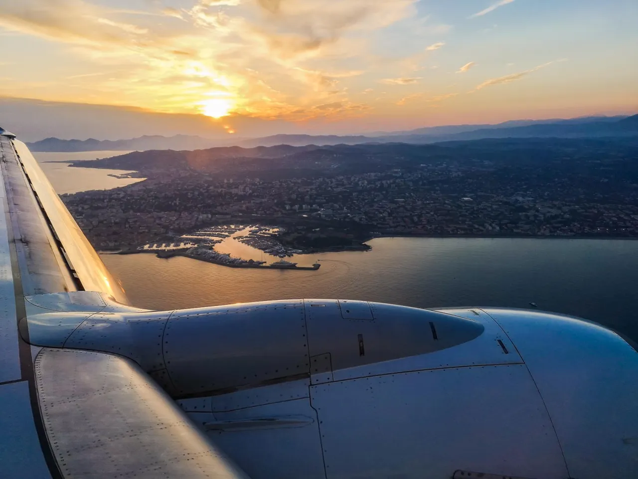 Widok z samolotu na wybrzeże Włoch o zachodzie słońca. Czy loty do Włoch są bezpieczne? Tak, ten widok potwierdza, że podróż jest warta zachodu.