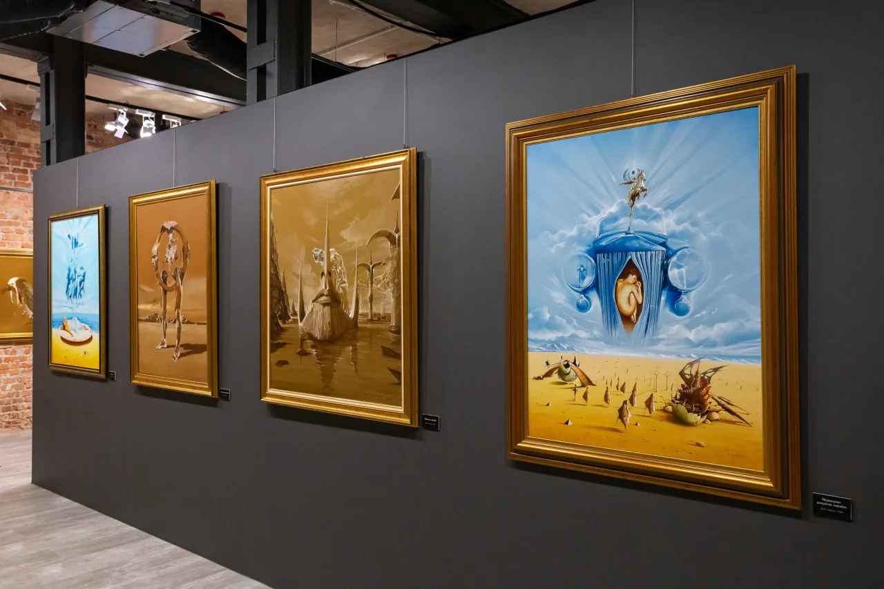 Obrazy w muzeum sztuki fantastycznej: surrealistyczne pejzaże i postacie w złotych ramach.