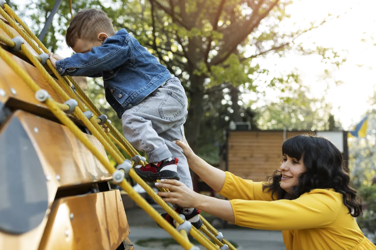 dzieci bawiące się bezpiecznie plac zabaw rodzic sprawdza sprzęt
