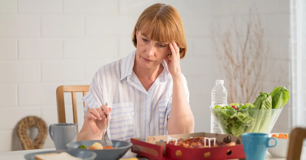 Osoba zamyślona przy stole, symbolizująca problemy z jedzeniem