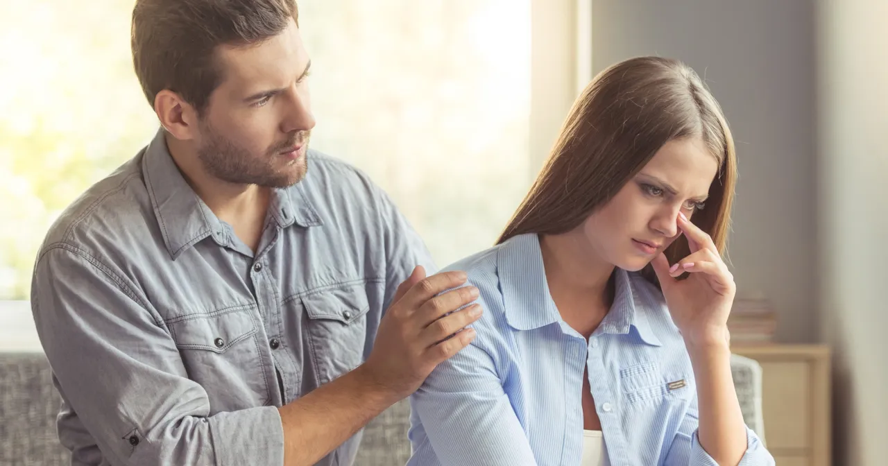 Mężczyzna pociesza smutną kobietę, kładąc jej dłoń na ramieniu. Szuka sposobu, jak przeprosić kobietę, żeby wybaczyła.