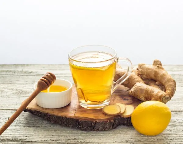 Dampfender Ingwer-Zitronen-Tee mit Honig in einer Glastasse