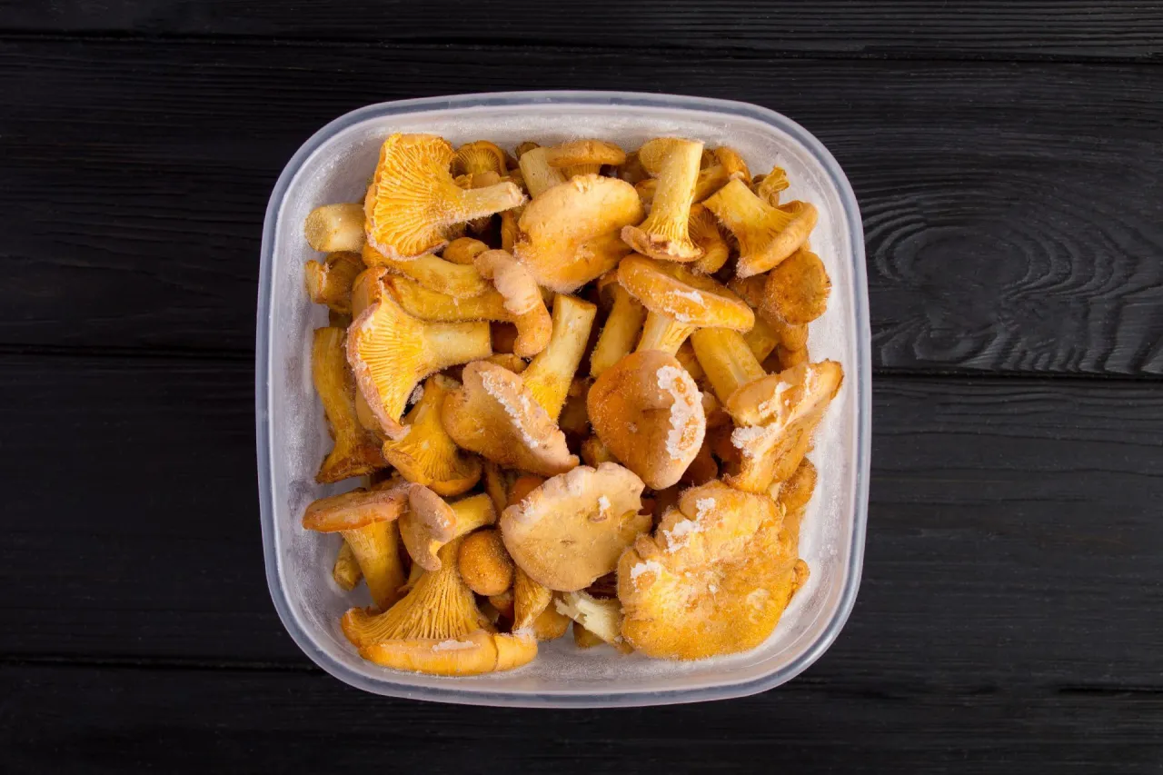 Sposób, jak mrozimy grzyby kurki, by zachować ich smak. W przezroczystym pojemniku widać zamrożone, żółte kurki.