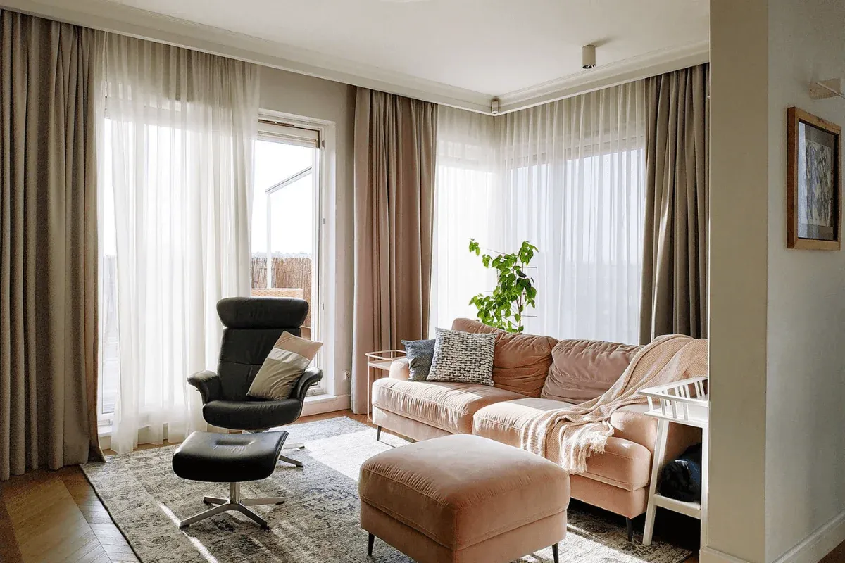 Wygodny pok&oacute;j dla seniora: rozkładana sofa, fotel z podn&oacute;żkiem, miękki dywan i jasne zasłony.