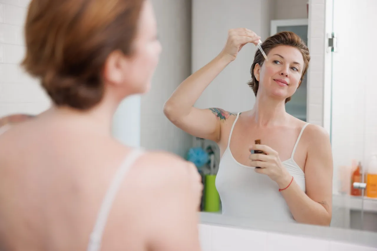 kobieta nakładająca serum z kwasem hialuronowym na twarz