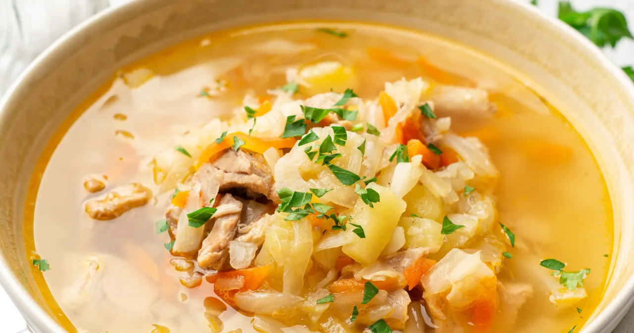 Gęsty, aromatyczny kapuśniak z mięsem, ziemniakami i marchewką, posypany natką pietruszki. Czy kapuśniak jest zdrowy? Tak, to sycące i pełne witamin danie!