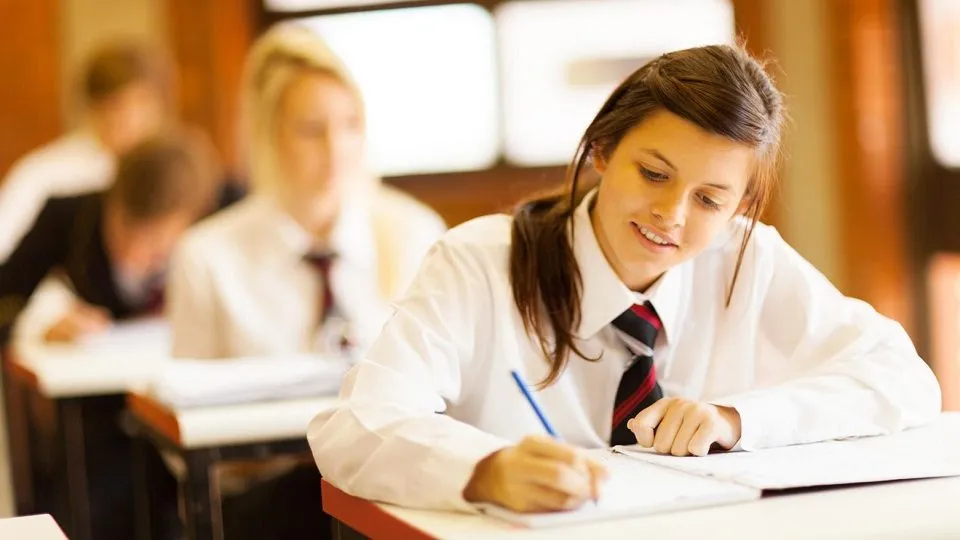 uczeń piszący egzamin z dodatkowym czasem na zegarze w tle