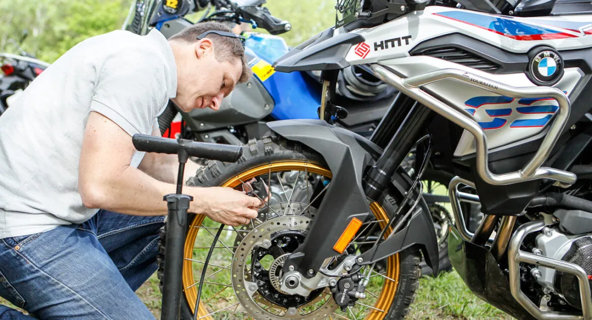 motocyklista zmieniający oponę w terenie