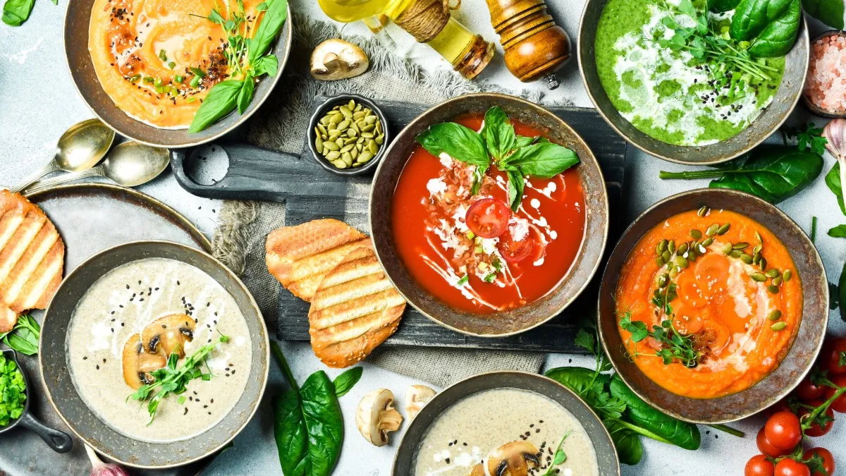 Verschiedene Schüsseln mit Suppen-Toppings wie frischen Kräutern, Croutons und gerösteten Kernen