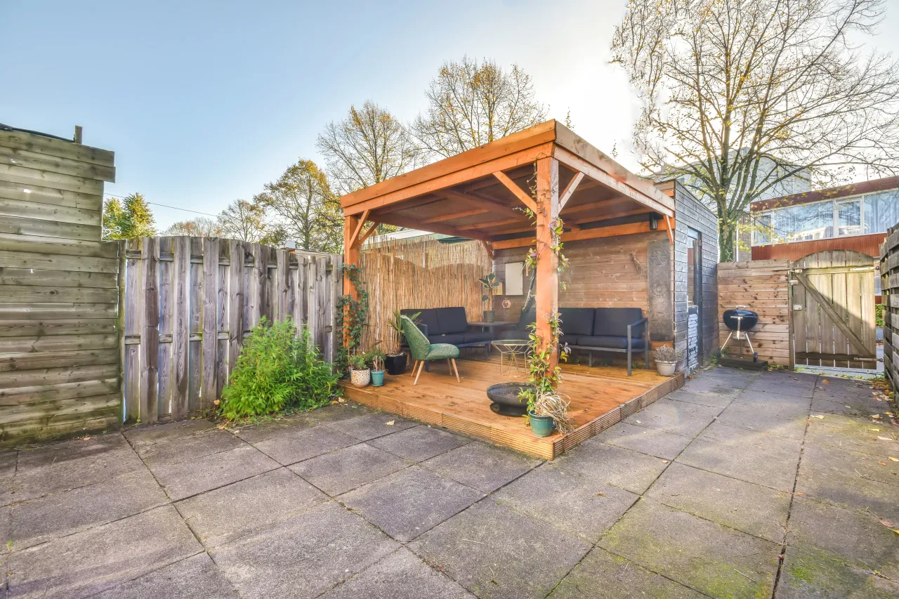 Drewniana altana z palet, z wygodnymi sofami i grillem, idealna na letnie wieczory.