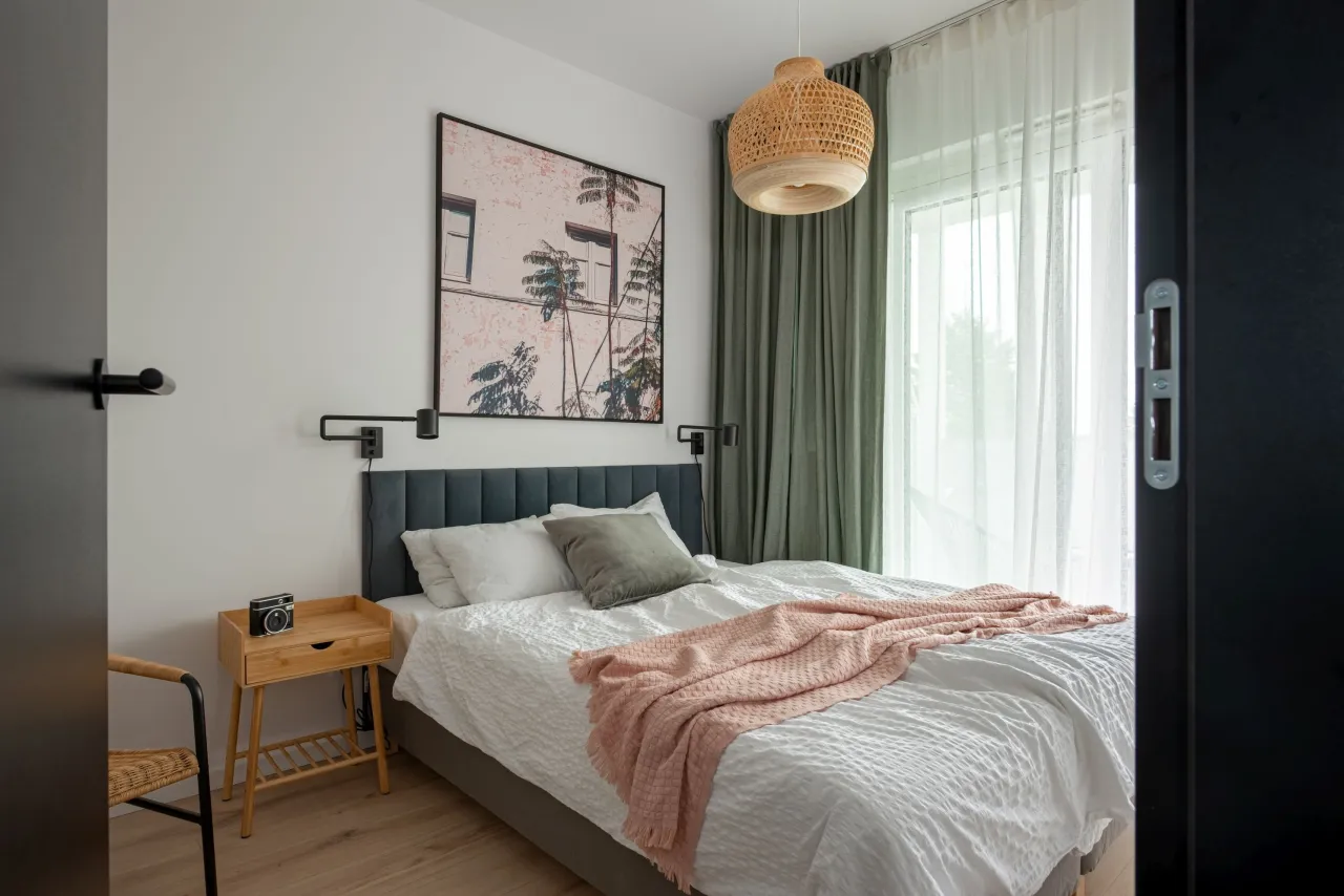 mała sypialnia z lustrem i jasnymi kolorami