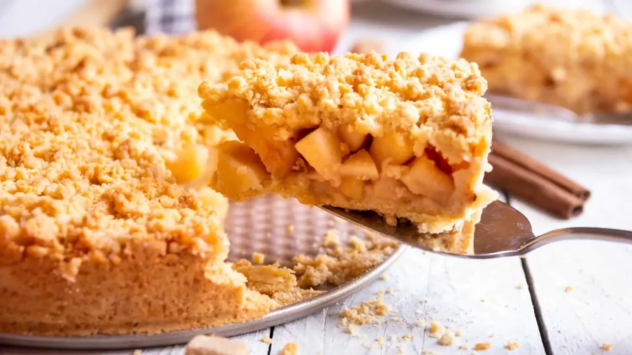 Kawałek szarlotki z rumianym kruszonką i kawałkami jabłek. Idealny sposób, jak smażyć jabłka na szarlotkę, by były soczyste.