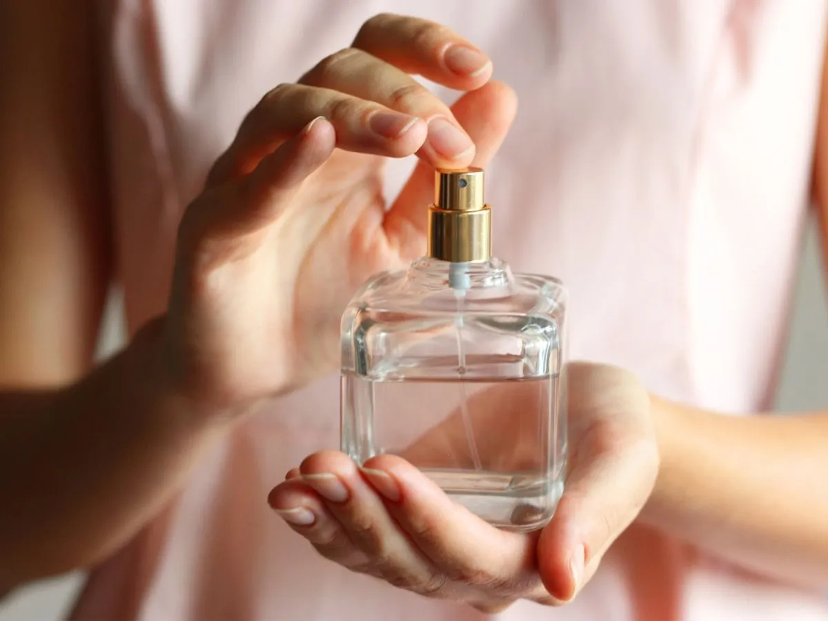 Elegancka kobieta aplikująca perfumy na nadgarstek, w luksusowej scenerii