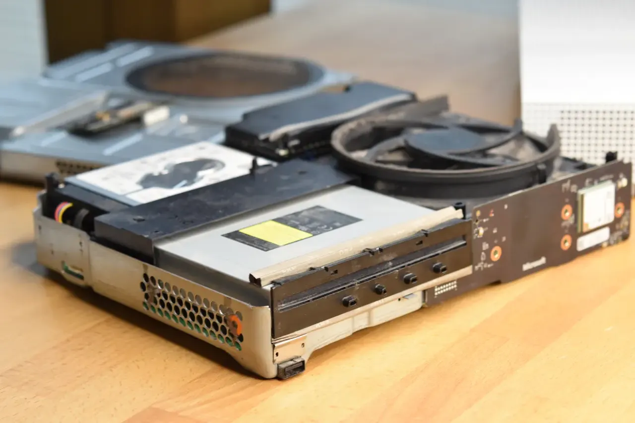 Rozłożona konsola Xbox z widocznym dyskiem twardym i wentylatorem. Zastanawiasz się, throttling co to? To zjawisko, gdy urządzenie obniża wydajność, by zapobiec przegrzaniu.