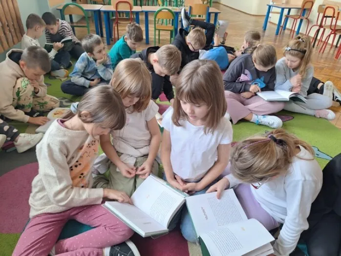 uczniowie w bibliotece szkolnej czytają