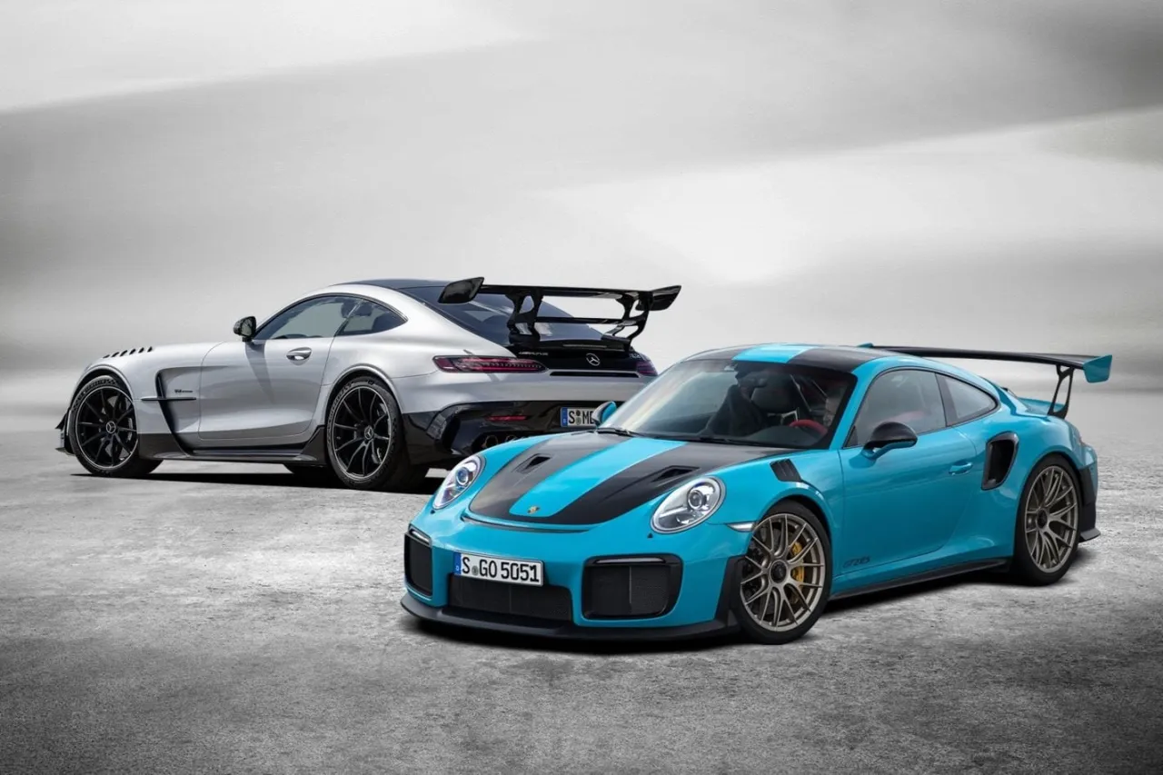 Dwa sportowe samochody: błękitny Porsche i srebrny Mercedes-AMG GTR PRO z dużym spojlerem, gotowe do wyścigu.