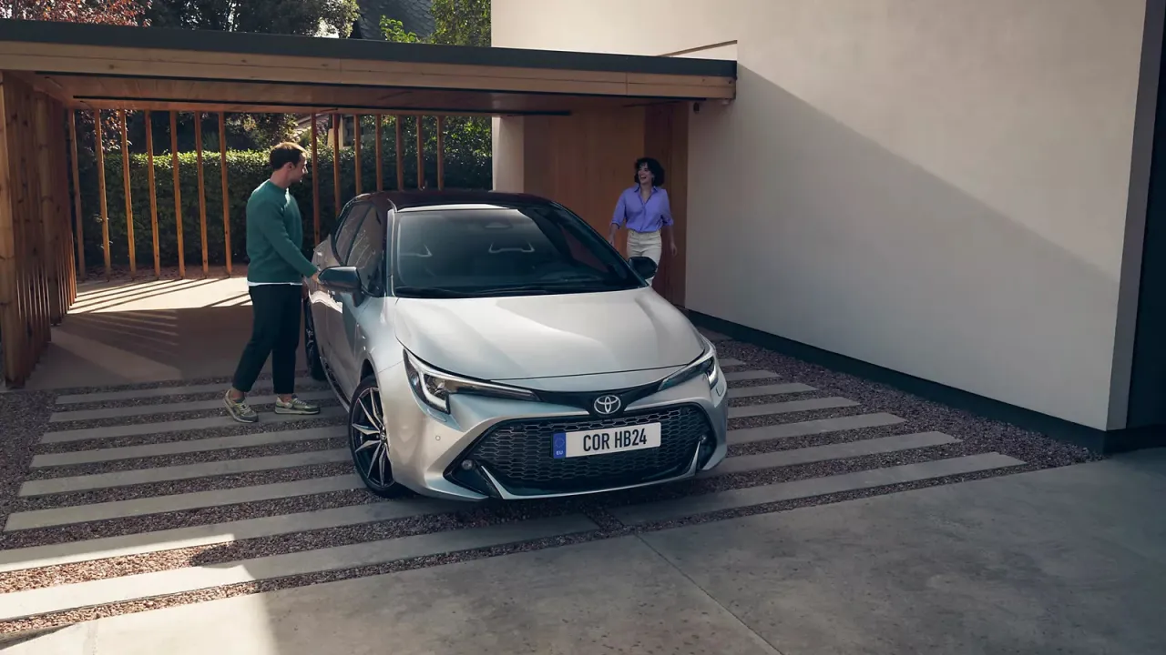 Para, kt&oacute;ra wsiada do swojego nowego, srebrnego auta. To jedne z pierwszych aut, kt&oacute;re tak pięknie prezentują się przed nowoczesnym domem.