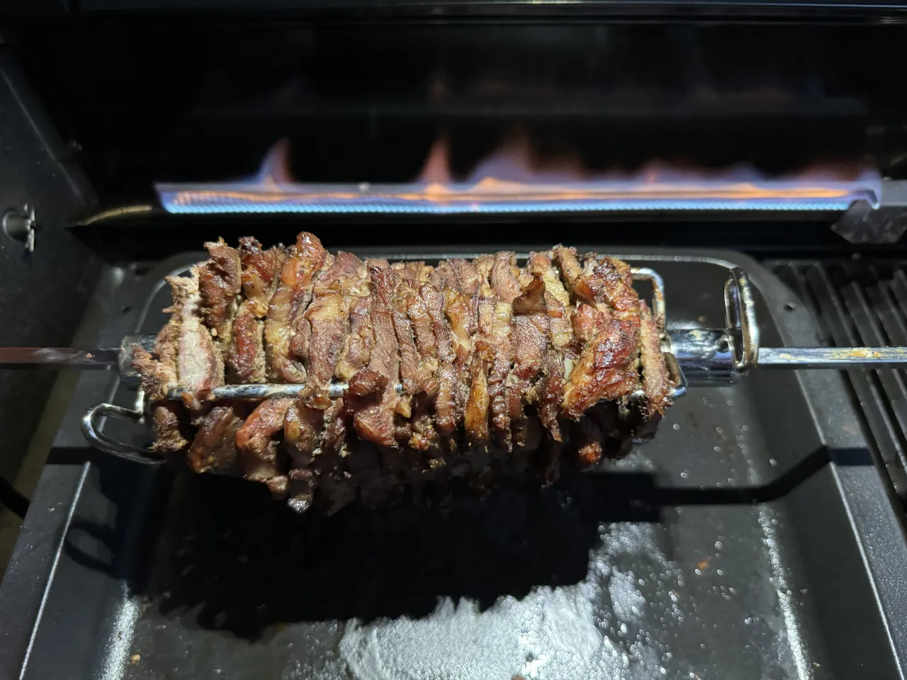 Soczysty kebab z wieprzowiny obraca się na rożnie nad płomieniami.