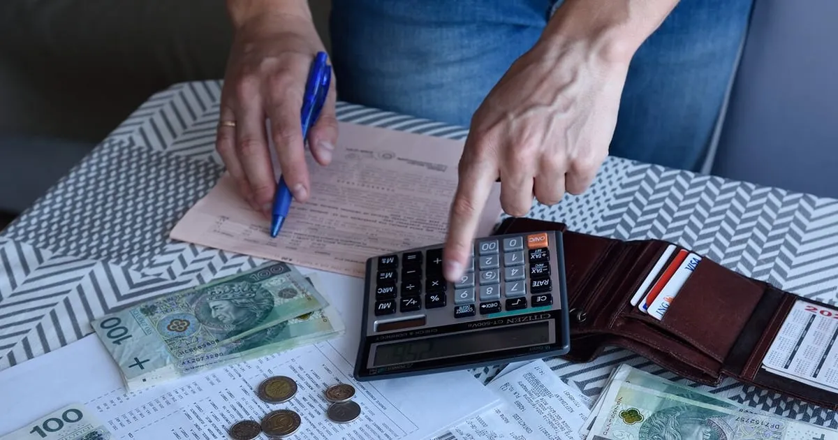 osoba zastanawiająca się nad podatkami od nieruchomości, kalkulator i dokumenty