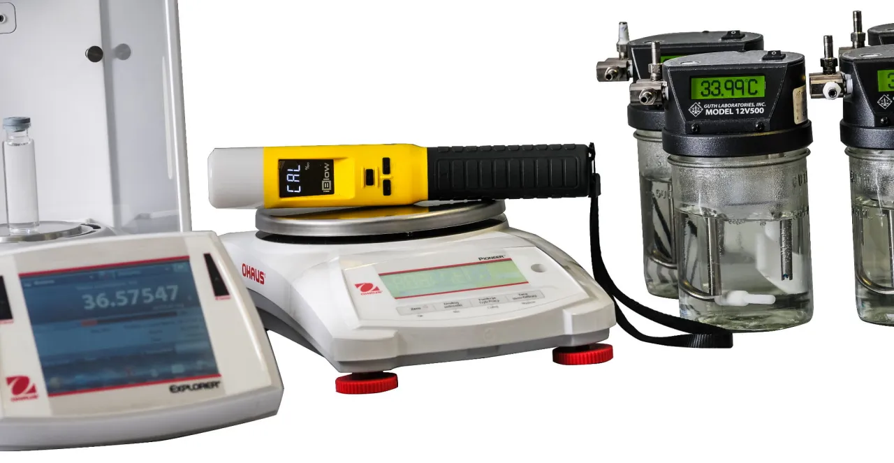 Żółty alkomat na wadze laboratoryjnej, obok probówki i kalibratorów. To pokazuje, ile trwa kalibracja alkomatu.