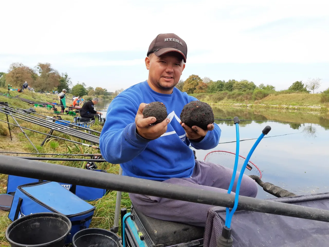 Wędkarz prezentuje zanęty Marcel na zawody. Dwie kulki zanęty w dłoniach, gotowe do rzutu.