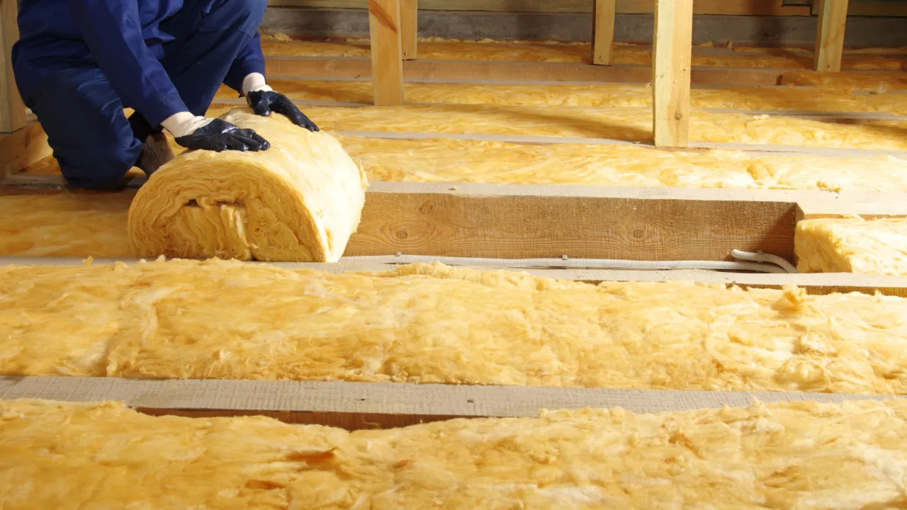 Pracownik układa wełnę mineralną na poddaszu. Czy ocieplenie budynku wymaga pozwolenia na budowę?