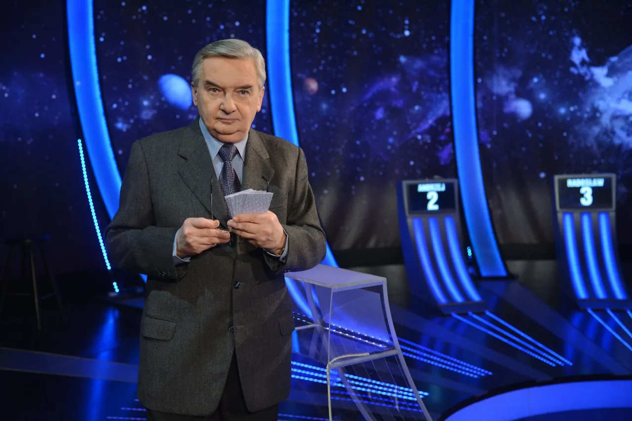 Tadeusz Sznuk, kt&oacute;ry prowadzi teleturniej Jeden z dziesięciu, stoi na tle kosmicznej scenografii.
