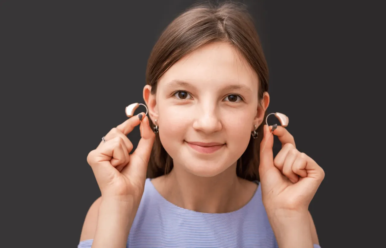 dziecko z aparatem słuchowym uśmiechnięte w szkole