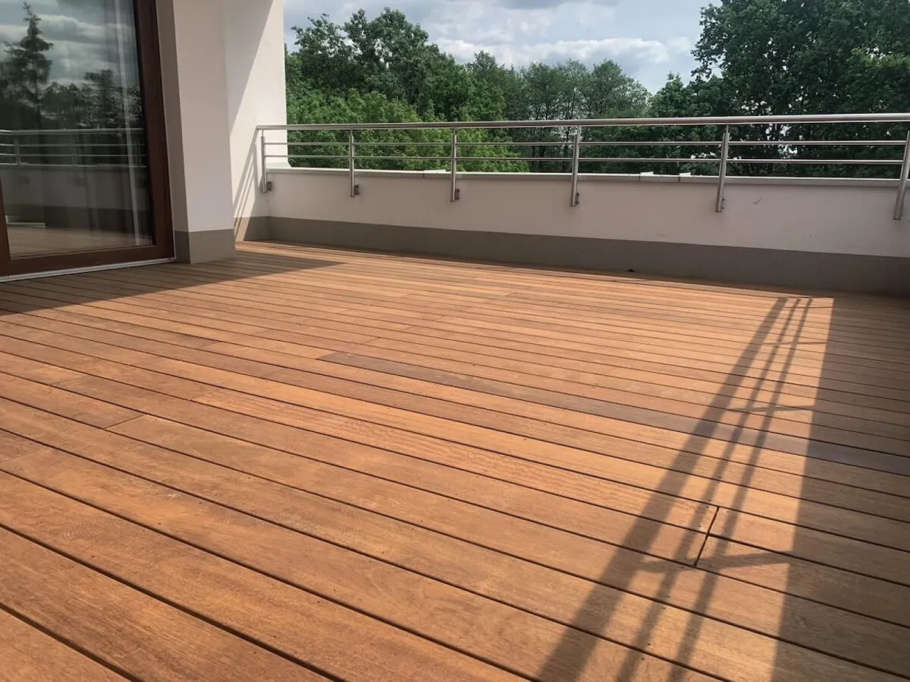 Nowy, drewniany taras z widokiem na zieleń. Zastanawiasz się, ile kosztuje budowa tarasu drewnianego?