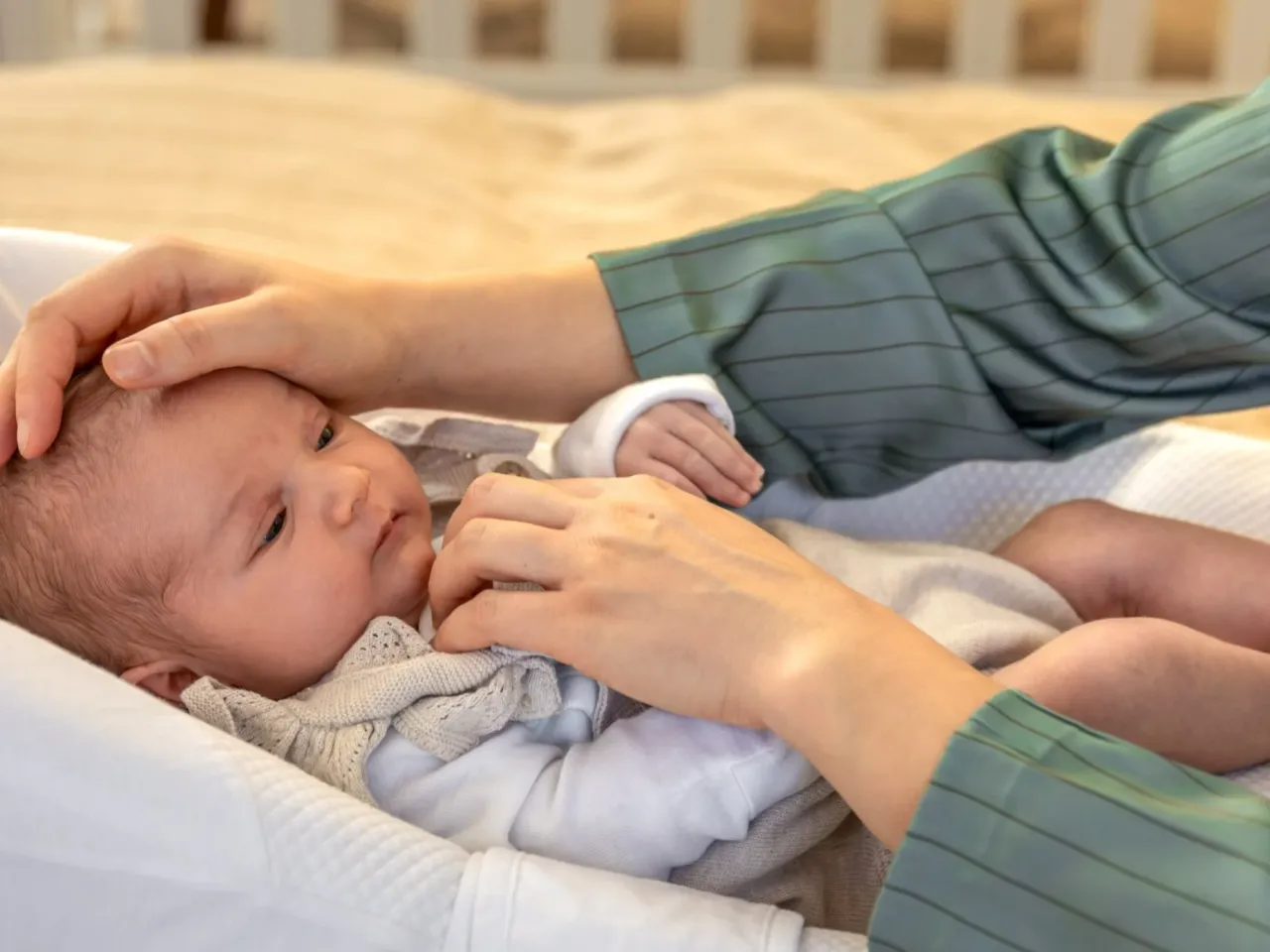 Delikatne dłonie rodzica czule dotykają główki noworodka. Czy to objawy RSV? Troska o zdrowie maluszka jest najważniejsza.