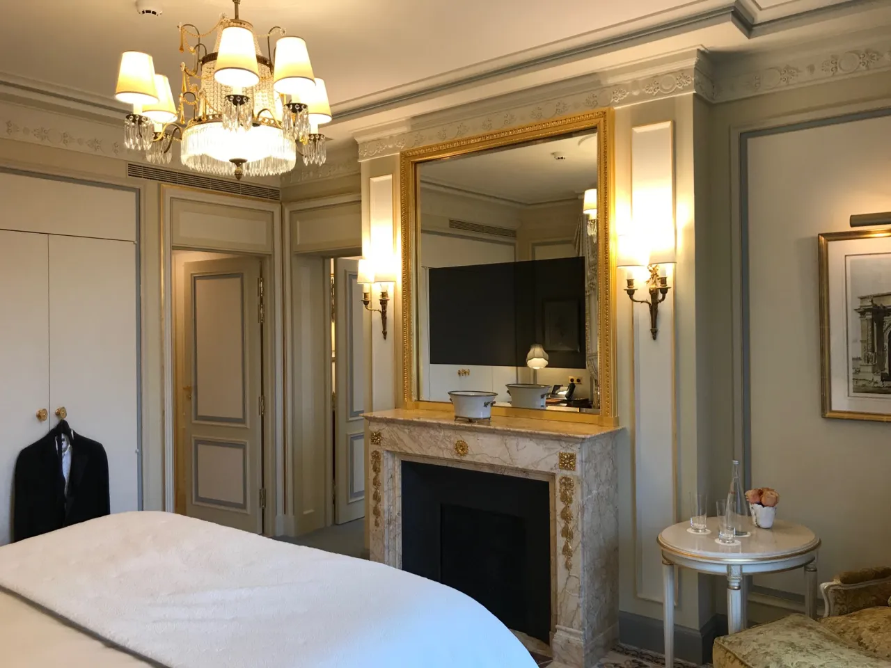 Elegancki pokój w hotelu Ritz Paryż. Marmurowy kominek, kryształowy żyrandol i stylowe meble tworzą luksusową atmosferę.